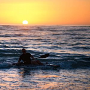 photo gallery man kayaking on a wave at sunset